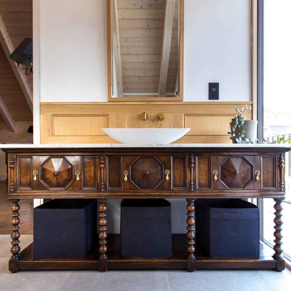 Drevené obklady stien v kúpeľni so starožitným stolíkom.